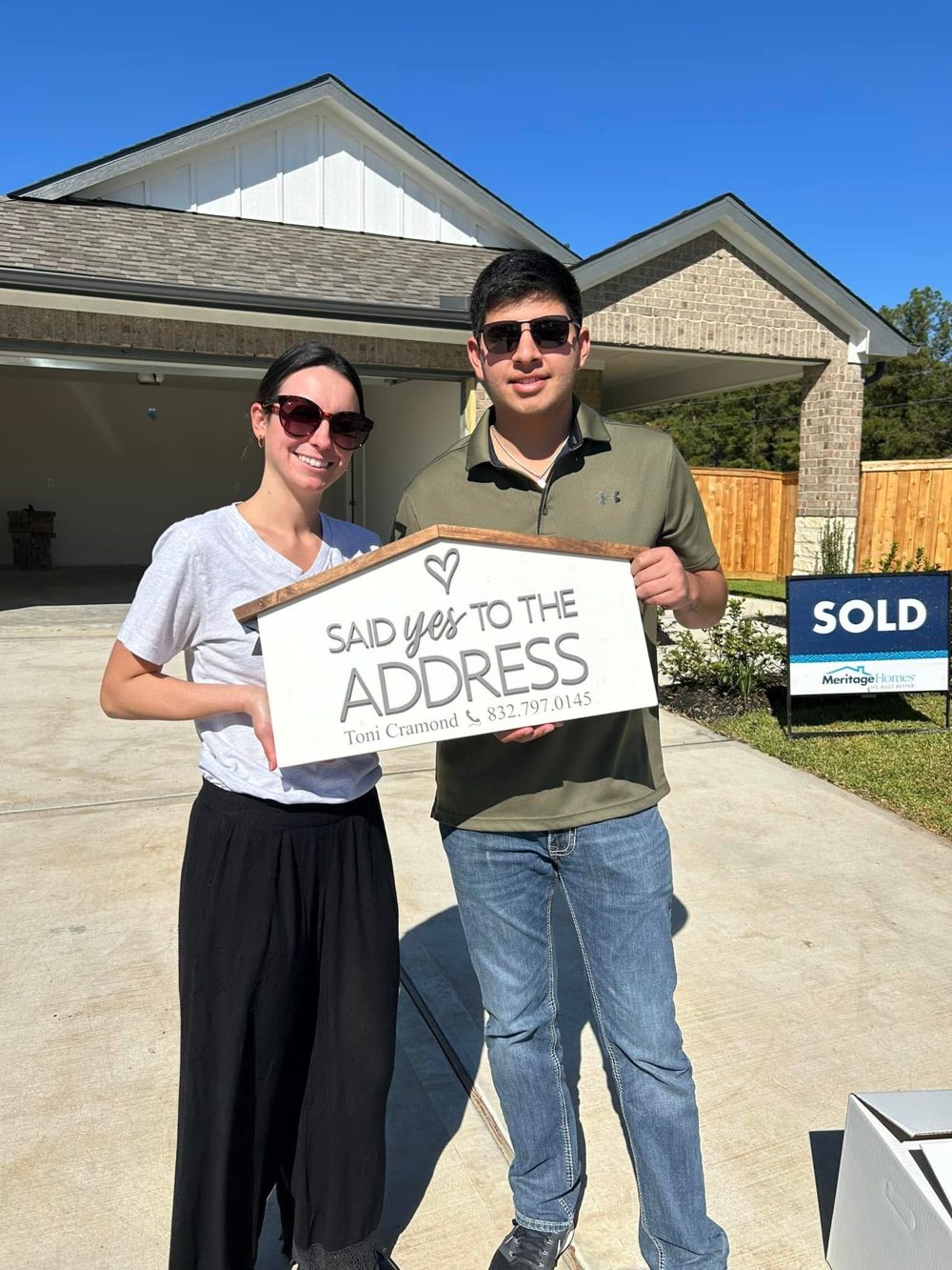 Buyers outside their new construction home holding a Said Yes to the Address sign